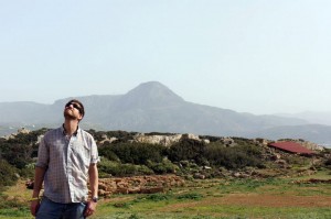 Man standing in a field with mountains behind