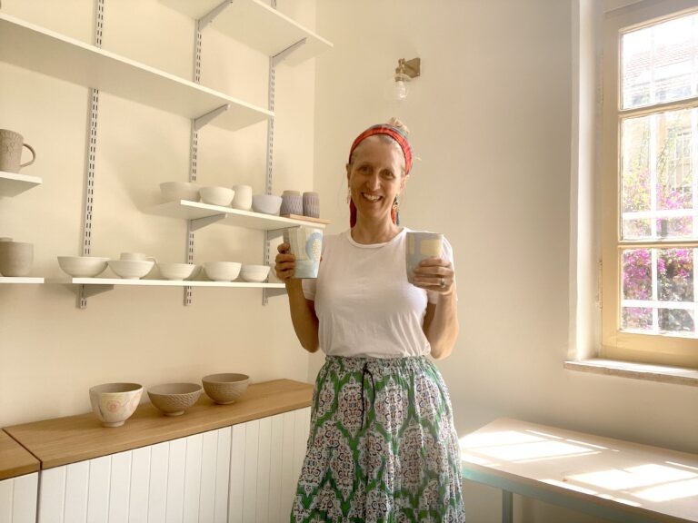 Woman in a sunlit kitchen holding two mugs