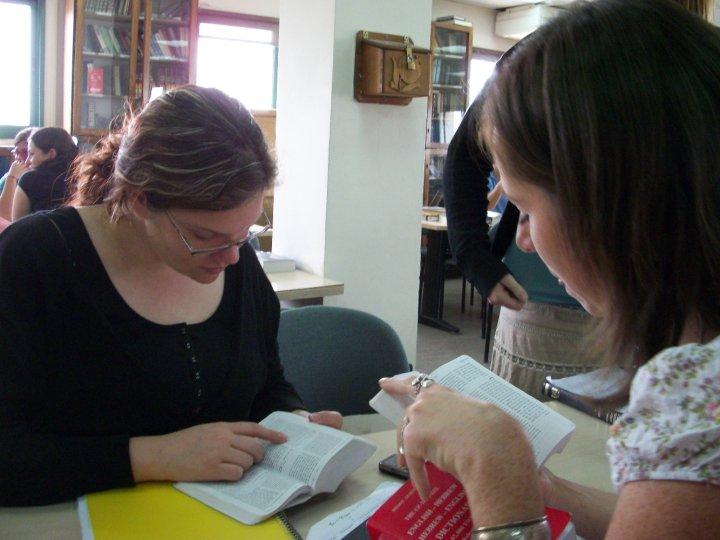 Women studying texts together at a table