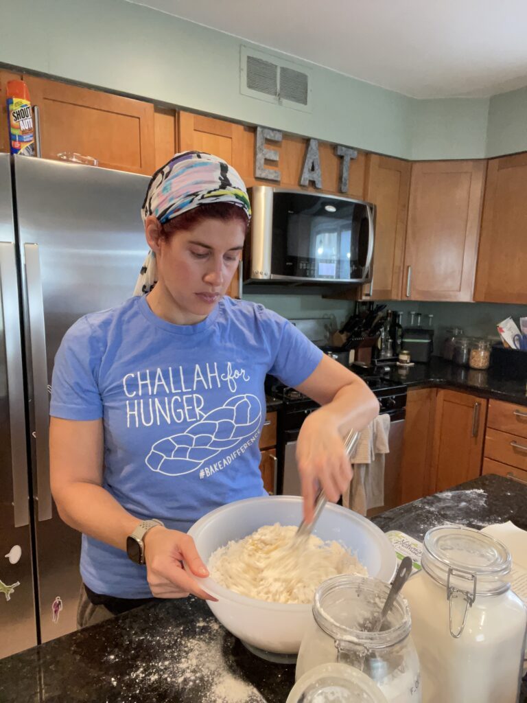 Young man in a "Challah for Hunger" T-shirt making dough in a kitchen