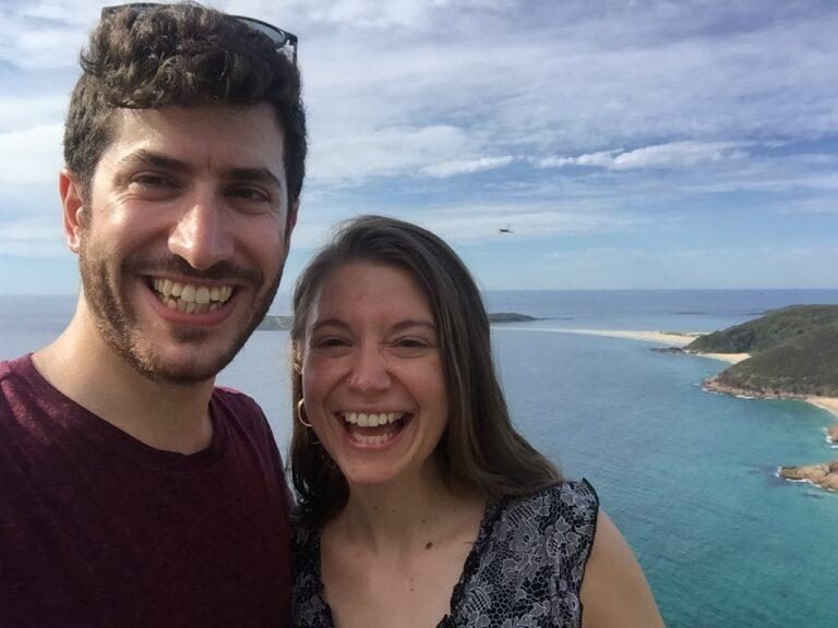 Adam Rossano and his wife smiling by the sea