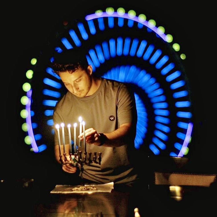 Jake Berger lighting a Hanukkah menorah at night