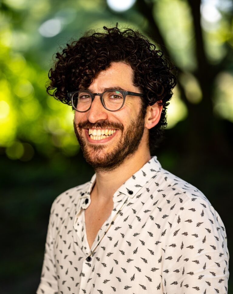 Smiling man with curly hair and glasses