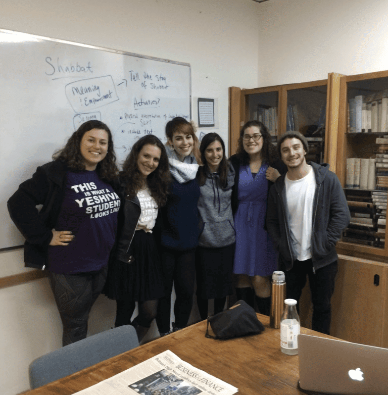 Group of students posing in an office with a whiteboard