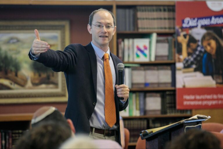 Speaker in a suit addressing an audience with a microphone