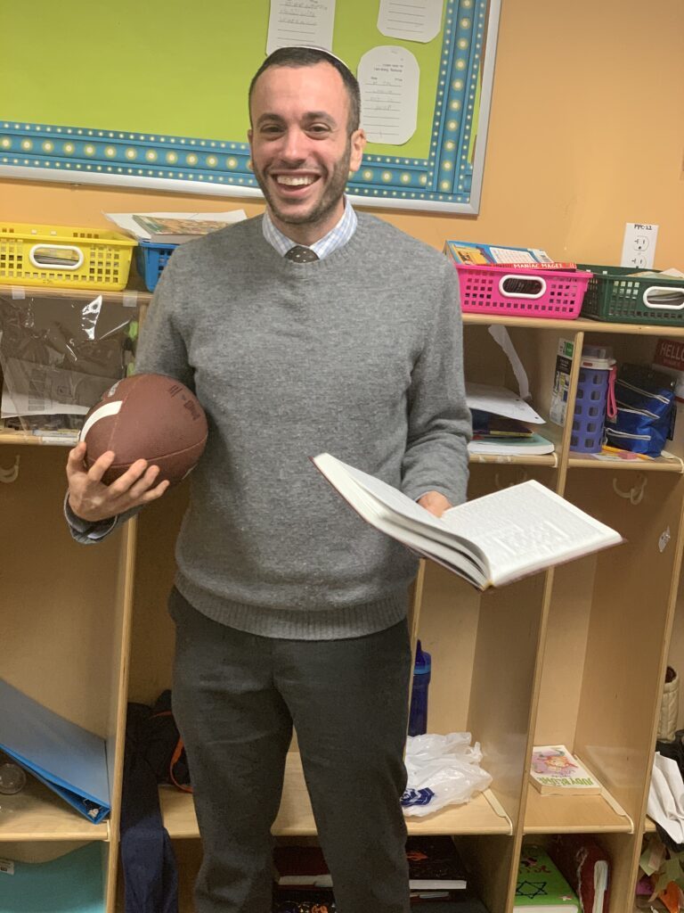 Jordan Soffer holding an open book in a classroom