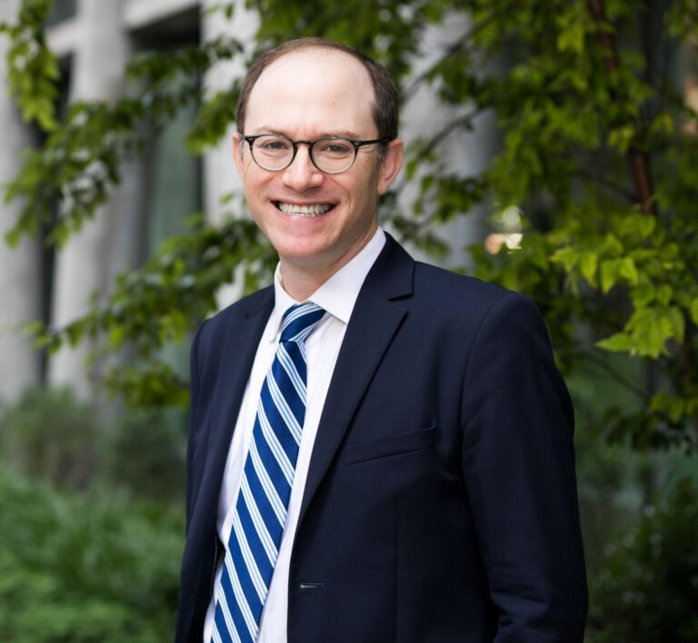 Smiling man in a suit and striped tie outdoors